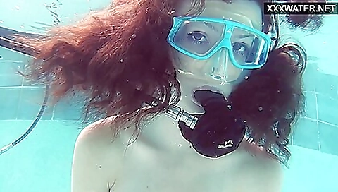 A brunette is in the pool and she is naked in the water